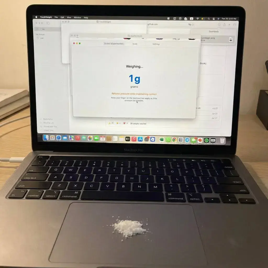 A MacBook Pro with a bit of white powder on the touchpad and with an app on the screen saying "Weighing... 1g"